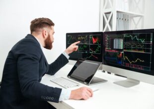 Mężczyzna analizujący wykresy na dwóch monitorach