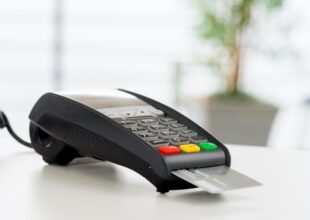Terminal płatniczy z włożoną kartą na białym stole